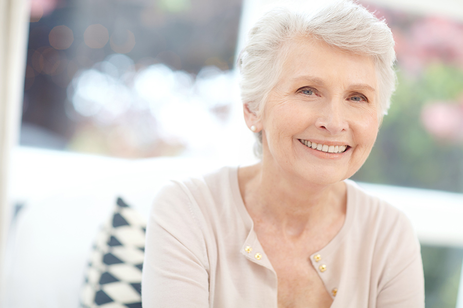 A happy senior woman smiling in a bright, home-like setting at Abbey Manor, a top choice for assisted living near Delaware City, DE.