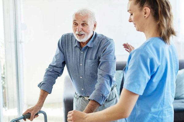 Caregiver assisting senior man in walking.