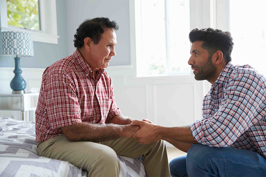 Putting a parent in assisted living concept image shows a son talking to his father regarding the move.
