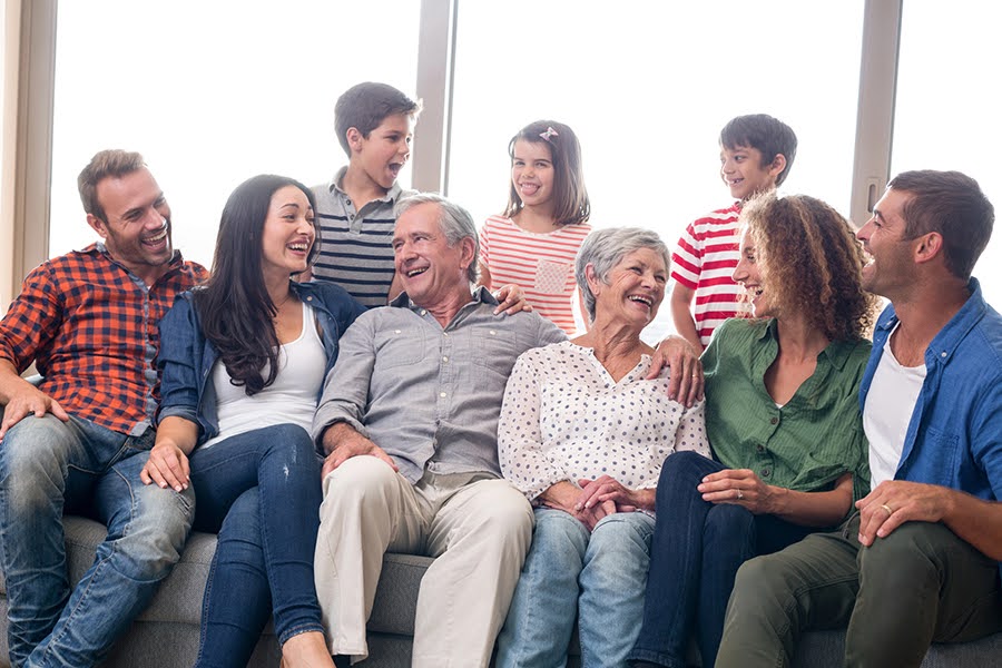 Smiling multigenerational family sitting on a couch, symbolizing support in end-of-life planning.