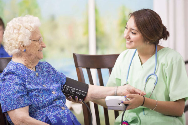 Young female care provider checking senior woman's blood pressure