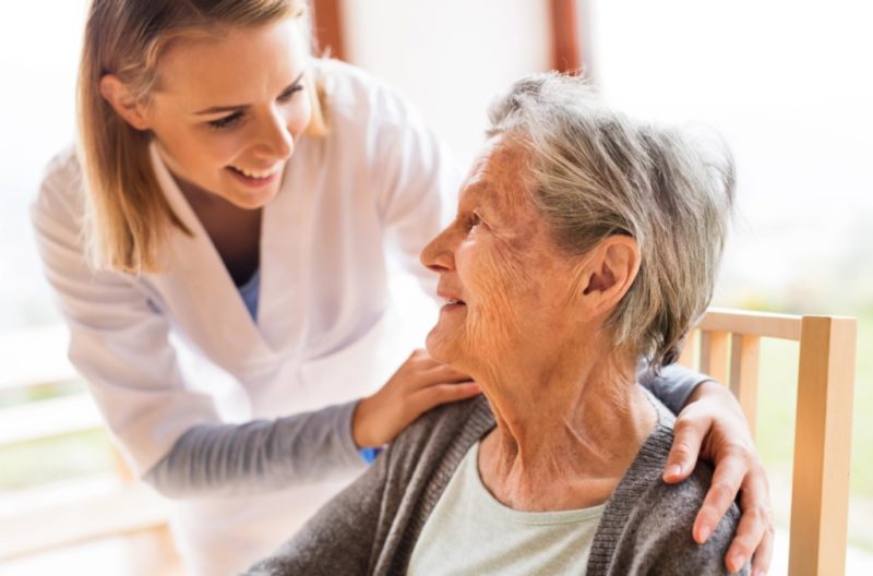 Caregiver helping a senior adult, illustrating the difference between assisted living and nursing home