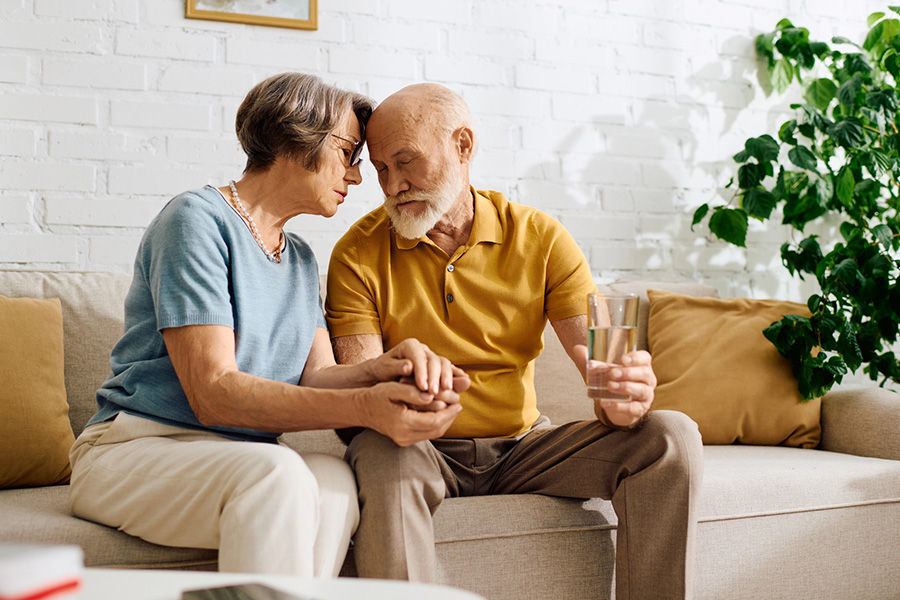 An elderly couple sitting on a sofa, providing support and comfort while considering respite memory care options