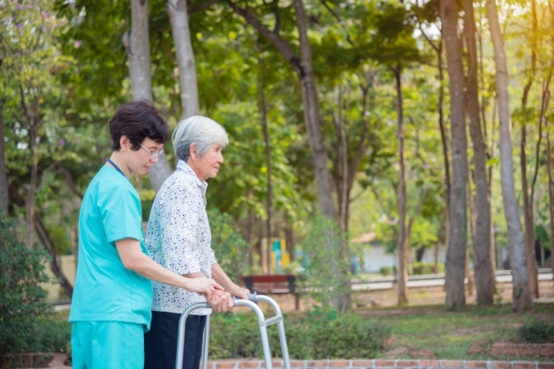 The caregiver is helping the elderly to walk in an assisted living environment