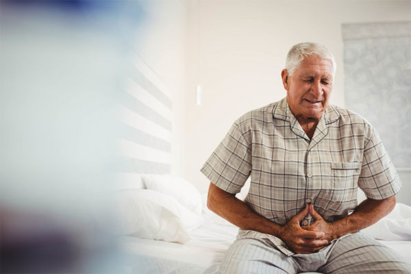 Elderly man holding his lower abdomen concept image for urinary track infection in seniors.