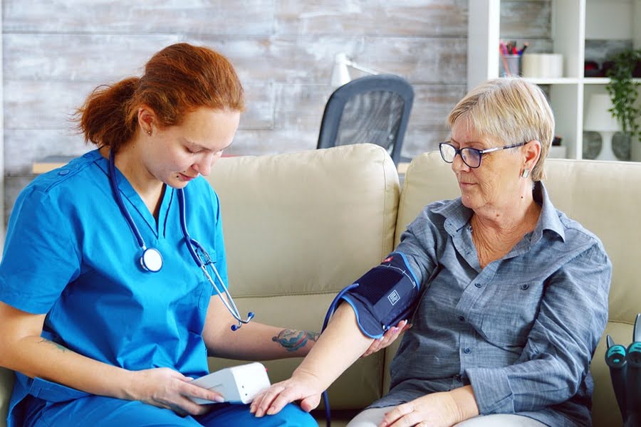 Nurse checking older woman’s blood pressure at Chesapeake Manor, providing care and monitoring for vascular dementia.