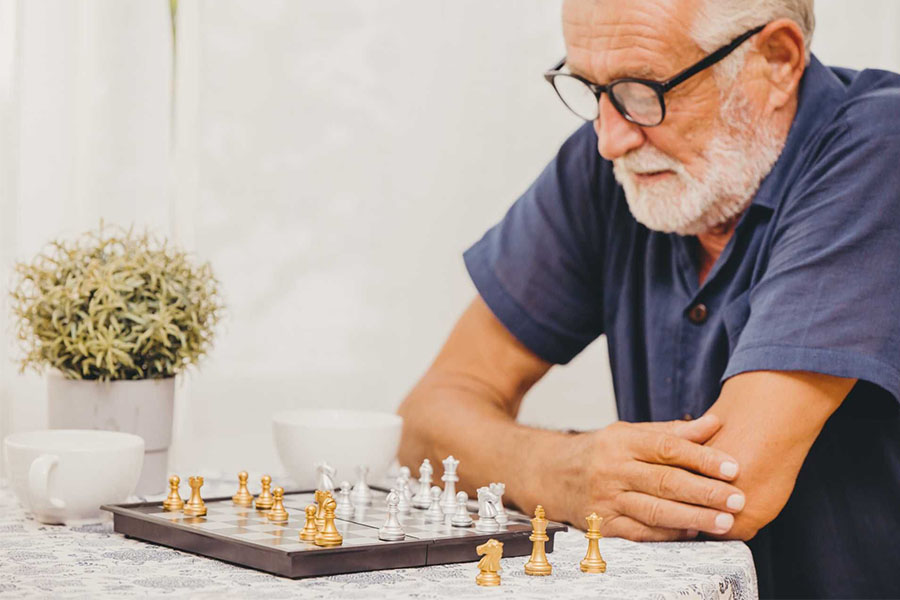 Senior man playing chess concept image on how to improve brain health.