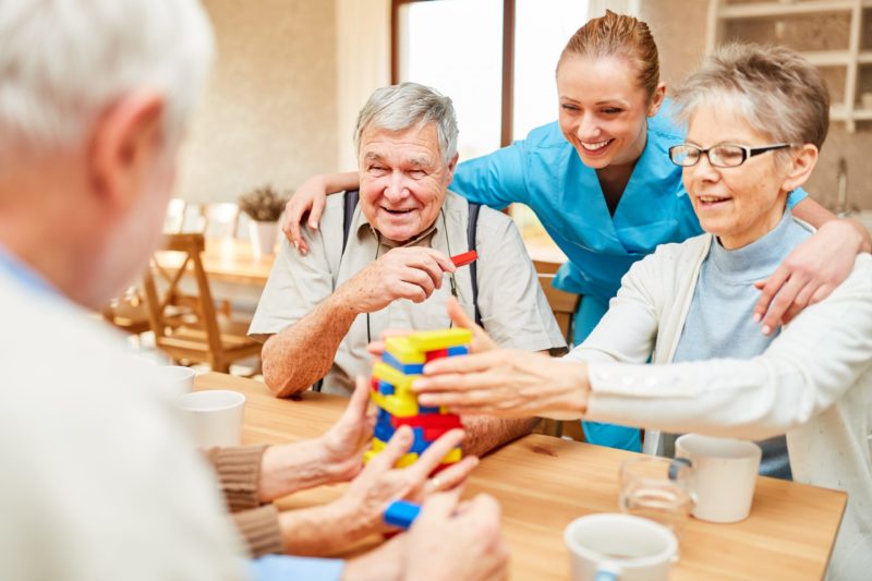 Senior people playing Jenga at our assisted living community near Berlin, MD. Health care provider having a conversation with the elder woman.