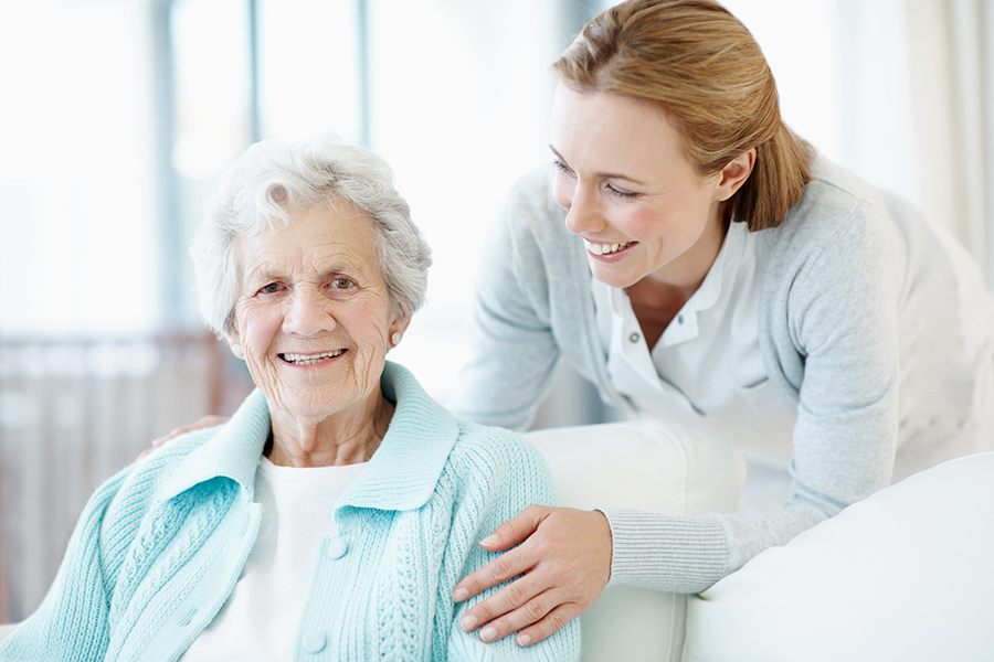 A compassionate staff member sharing a warm moment with a smiling senior resident at a supportive care community.