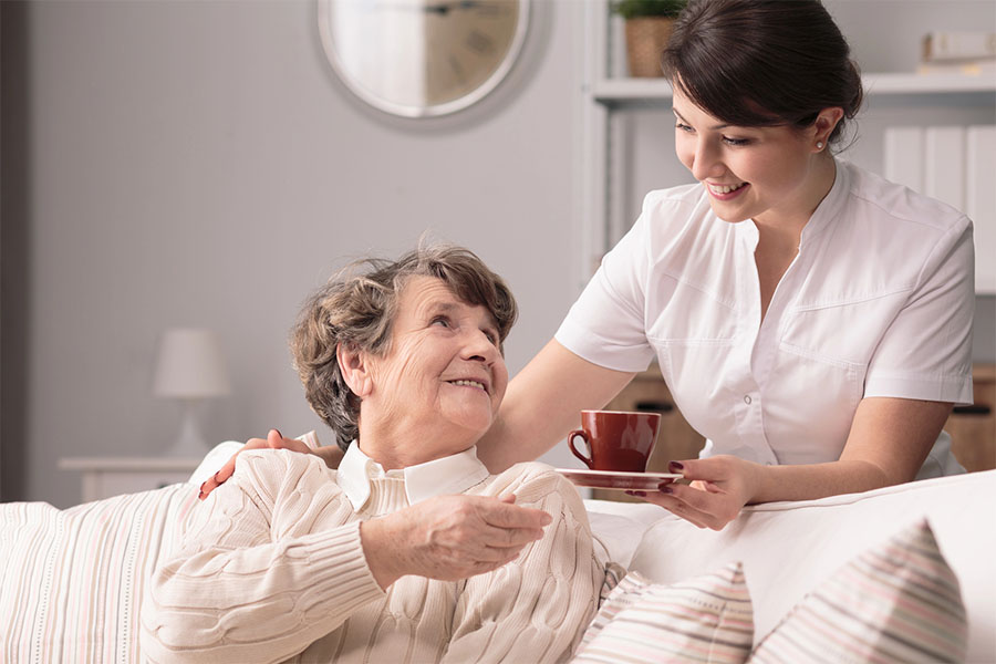 A dedicated caregiver offering supportive, attentive service to an elderly woman inside a comfortable senior living near selbyville, delaware.