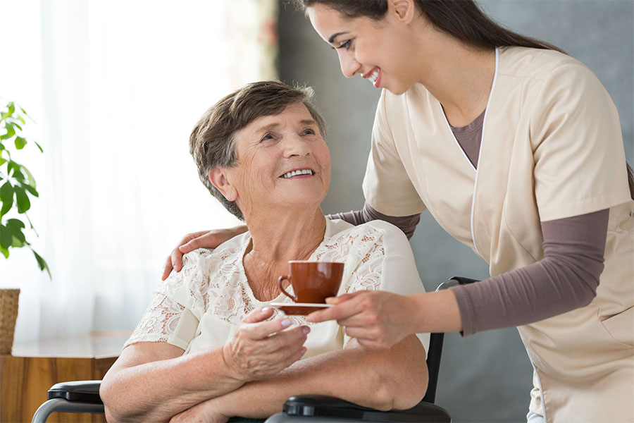 Caregiver discussing care plans with elderly woman in bed, illustrating when to move from assisted living to memory care
