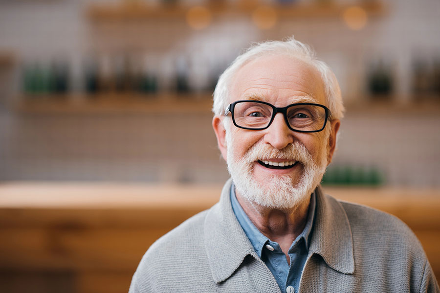 A smiling, cheerful senior man wearing glasses, reflecting the vibrant lifestyle and personalized support at our senior community near Selbyville.