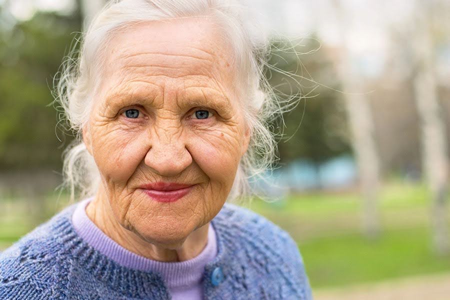 A smiling, dignified elderly woman outdoors, reflecting the peace of mind offered by Catered Living at Ocean Pines