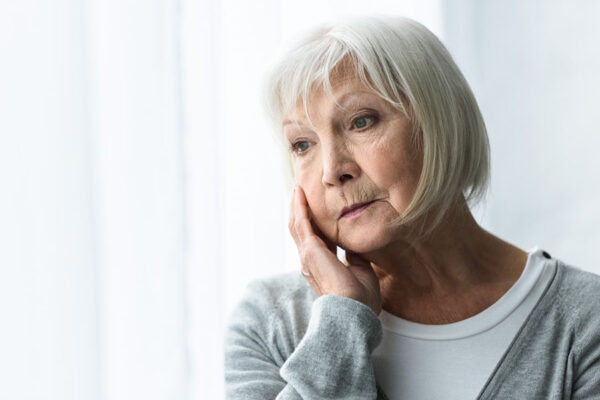 An elderly woman looking puzzled, representing someone with memory loss.