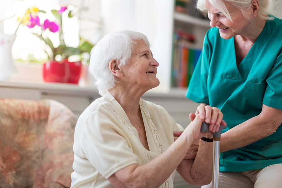 Caregiver helping an older woman with a cane in Memory Care near Bishopville, MD