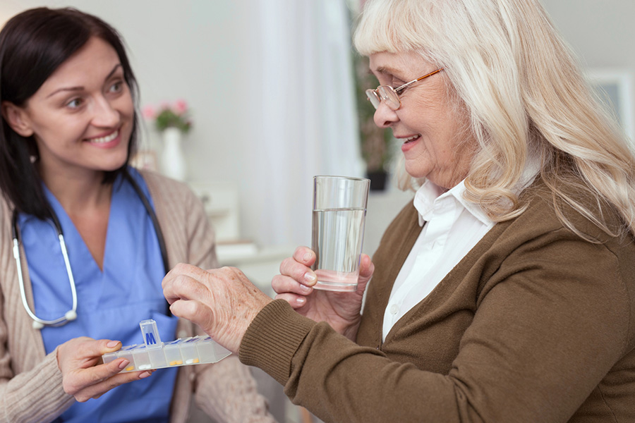 Healthcare worker assisting senior with medication to help prevent medication errors in assisted living setting.