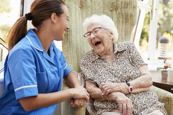 Senior woman and caregiver having a laugh concept image for personalized care.