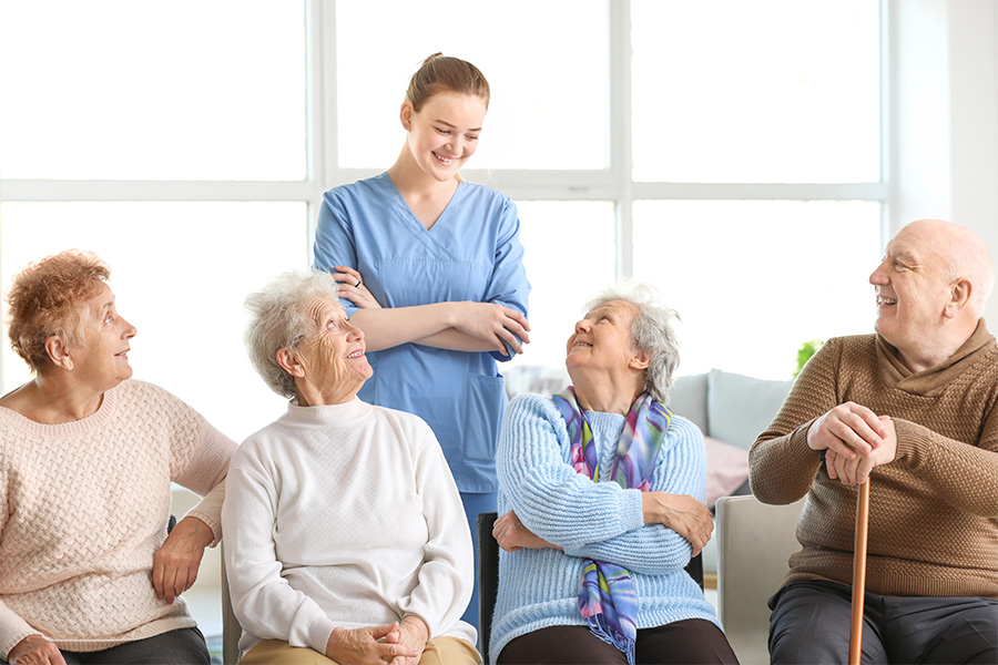 Seniors enjoy a social gathering with a smiling caregiver at an assisted living near Berlin, MD